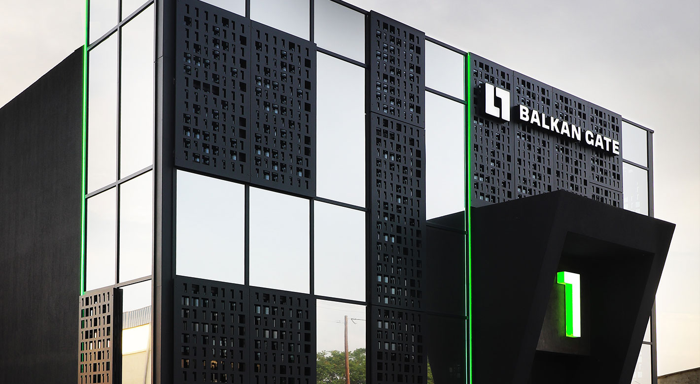Exterior view of Balkan Gate Thessaloniki Data Center with black-and-glass architecture and illuminated signage.